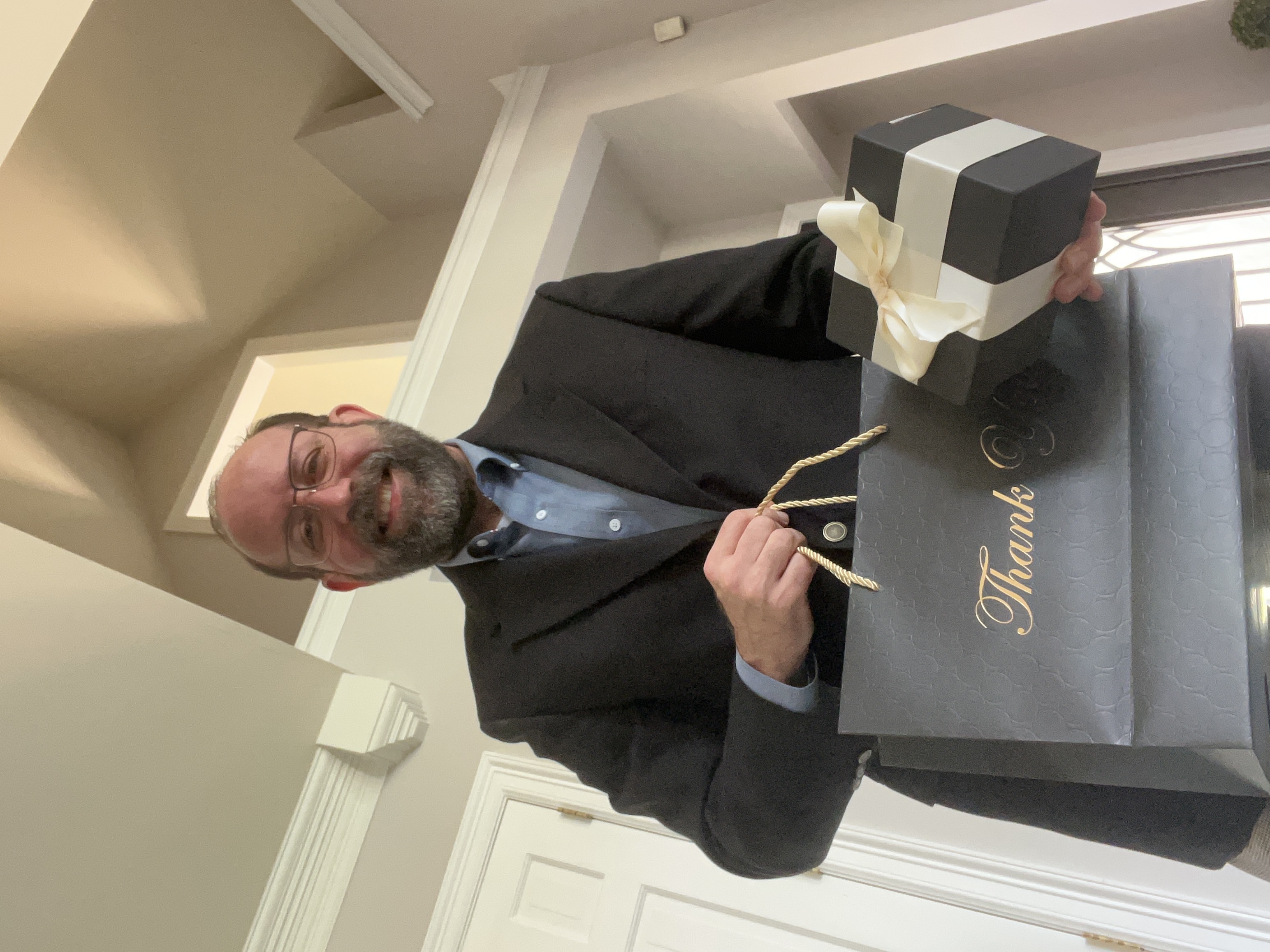 Robert holding a gift bag and a ribbon-wrapped watch box